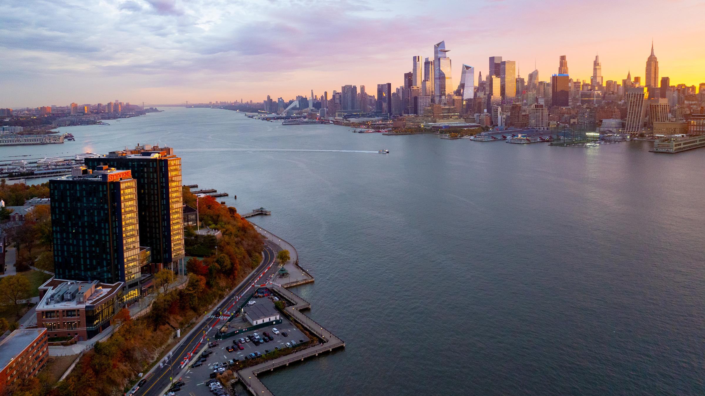 Aerial view at sunrise of the Stevens campus on the Hoboken waterfront with the Manhattan skyline across the Hudson River